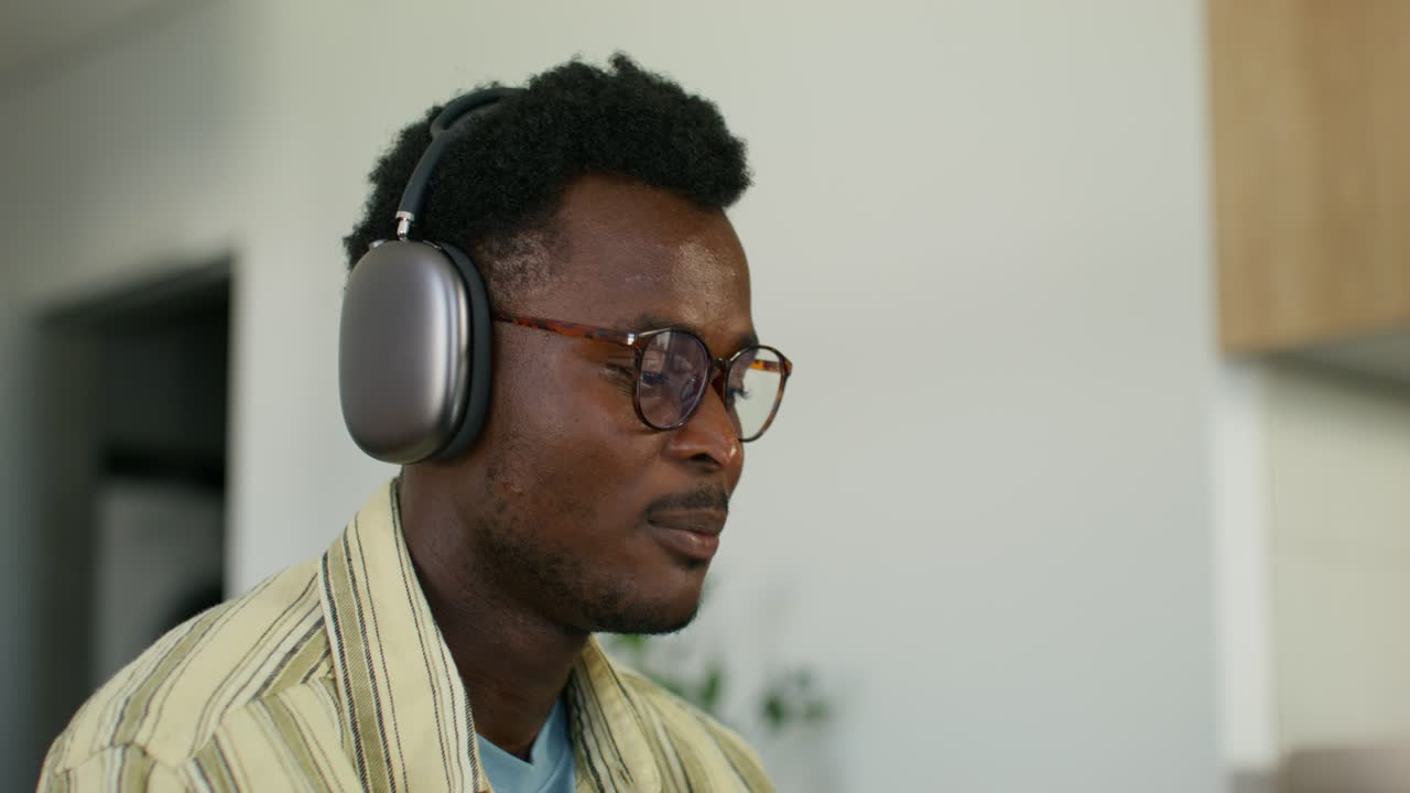 Man wearing headphones and glasses, listening to music at home