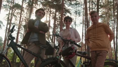 Joven-Pareja-Cariñosa-Con-Su-Hijo-Mirando-A-La-Cámara-Con-Sus-Bicicletas-En-Un-Entorno-Rural