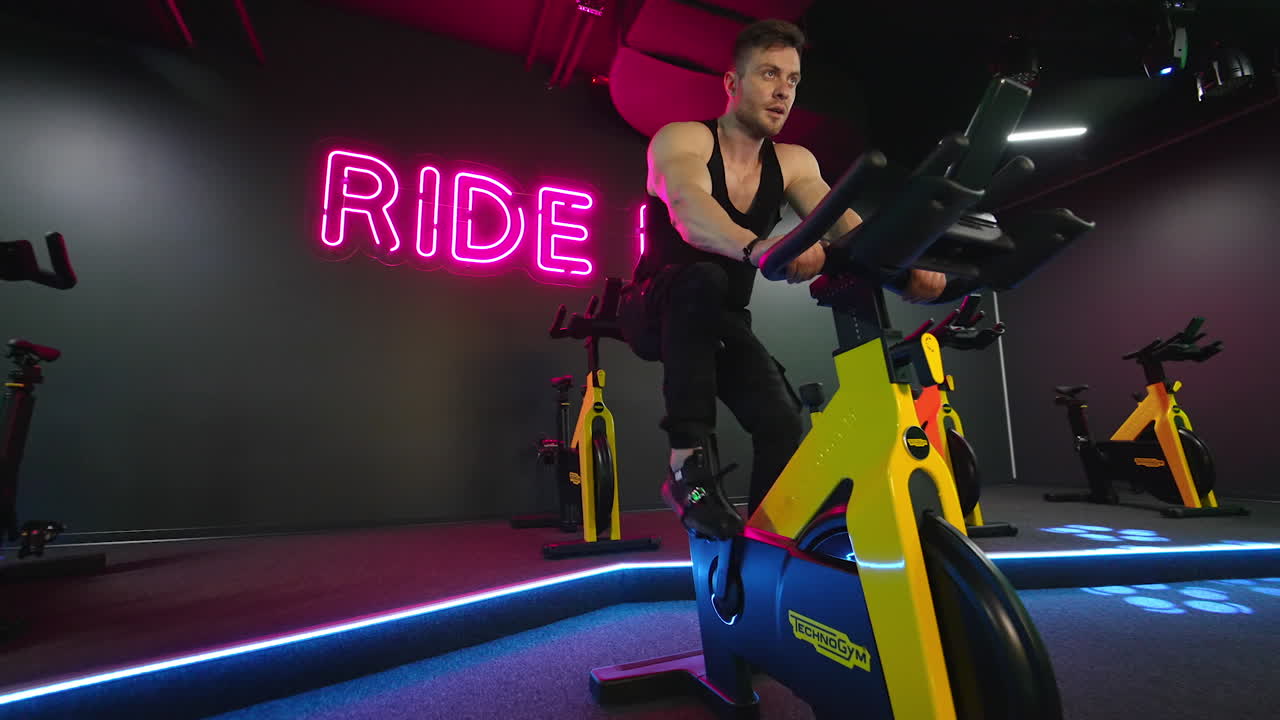 Man exercising in fitness club. Muscular athletic bodybuilder fitness man sitting stationary bicycle in gym