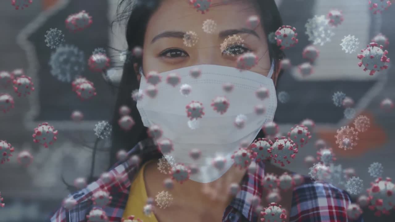 Animation of macro Covid-19 cells floating over Asian woman wearing a face mask