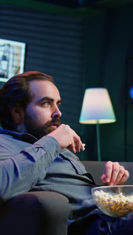 vertical video man at home surprise by film ending, unable to believe eyes, dropping popcorn