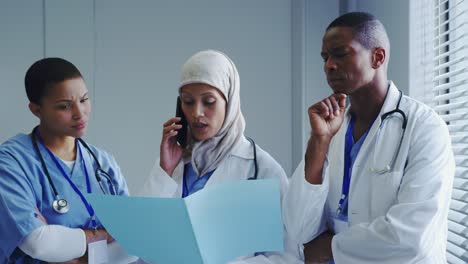 front view of middle-east female doctor talking on mobile phone with her colleagues in hospital