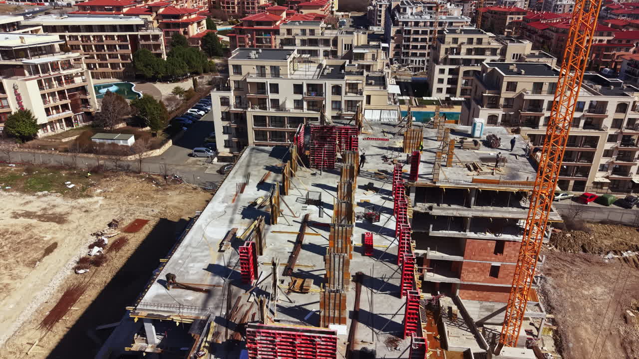 Costruzione di un nuovo edificio residenziale in un'area urbana con gru e operai sul cantiere durante le ore diurne.