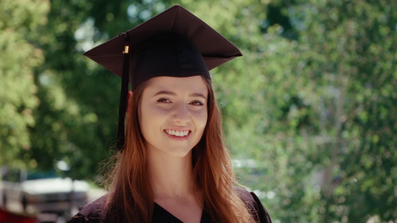 Female graduate student slowly turns her head and smiles at the camera.