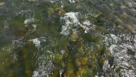 Top-down-shot-of-a-shallow-river-flowing-over-a-bed-of-rocks