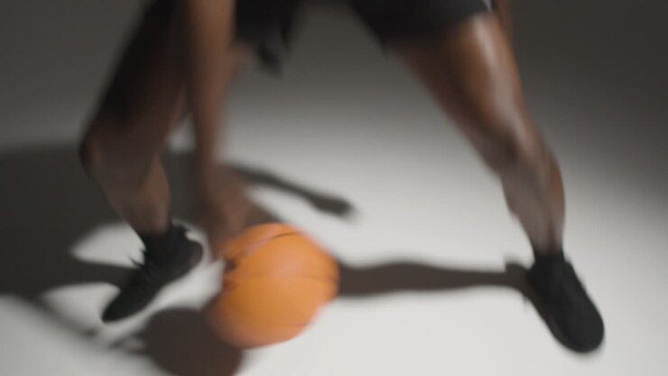 Studio-Action-Aufnahme eines männlichen Basketballspielers, der den Ball vor weißem Hintergrund dribbelt 1