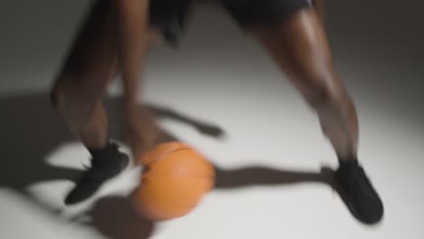 studio action shot of male basketball player dribbling ball against white background 1