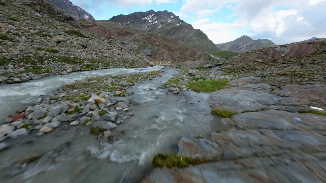 vuelo libre de drones sobre un puente y un torrente de agua que fluye en el glaciar fellaria en valmalenco de valtellina, italia