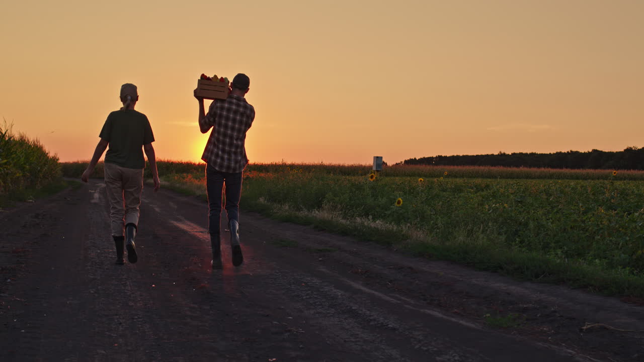 Farmers carrying produce at sunset