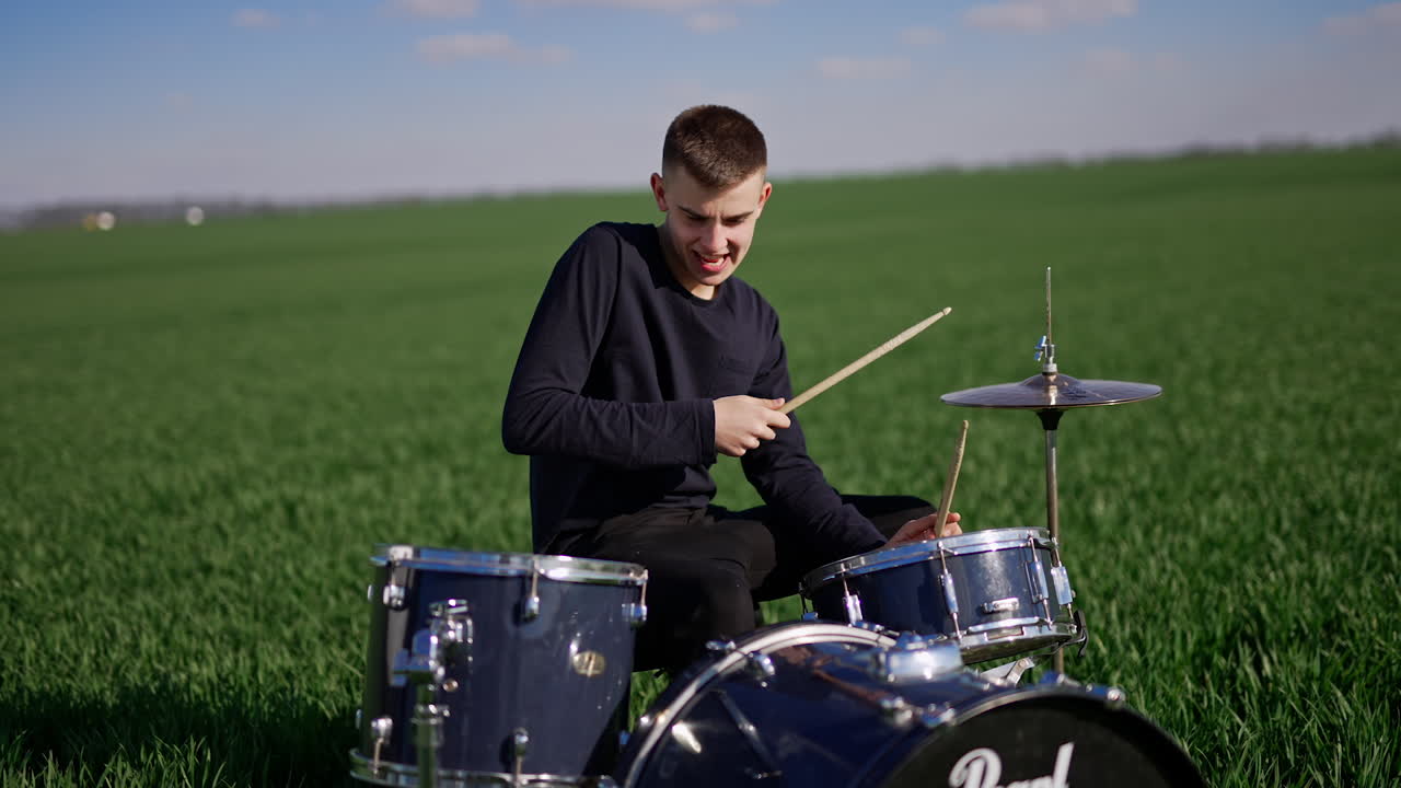 Teenager playing drums in a field