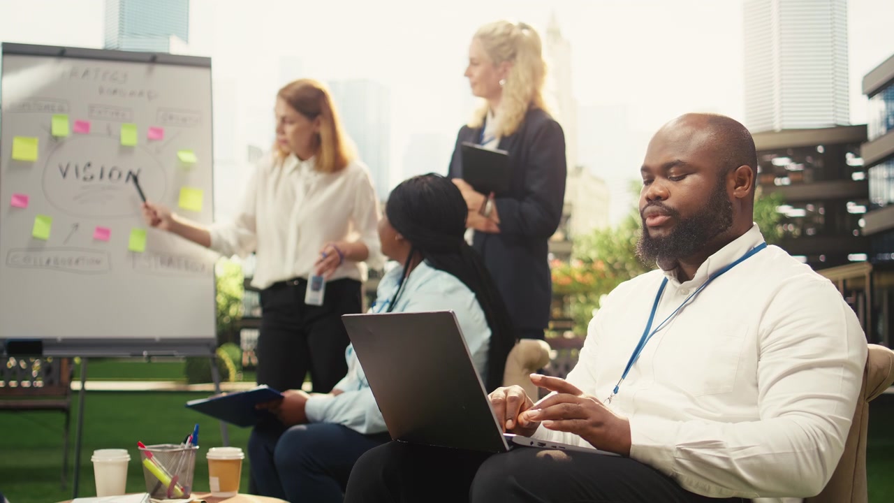 Fokussierter Geschäftsmann arbeitet am Laptop während eines Outdoor-Büromeetings