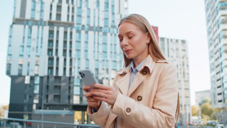 mature woman looking for search way on map in mobile navigator app against modern building in city