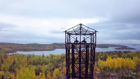 aerial-orbit panning shot of an abandoned mine headframe in the boreal forest in the fall with a lake in the background