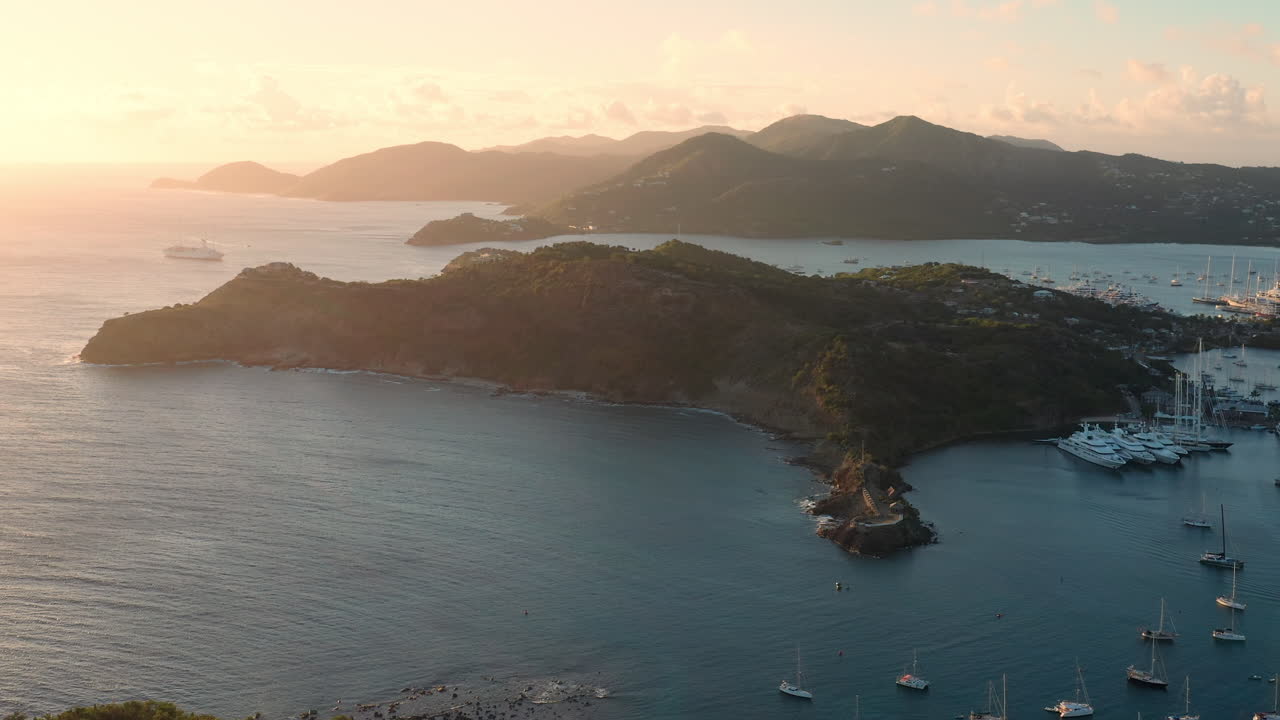 toma aérea de la puesta de sol en puerto inglés en antigua, caribe con vistas de yates, veleros, puerto deportivo, bahía y acantilados