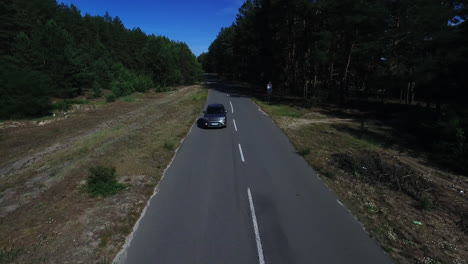 Drohnenaufnahmen-Beim-Autofahren-Auf-Einer-Fahrt-Im-Wald.-Silberner-Jeep-Fährt-Auf-Der-Forststraße