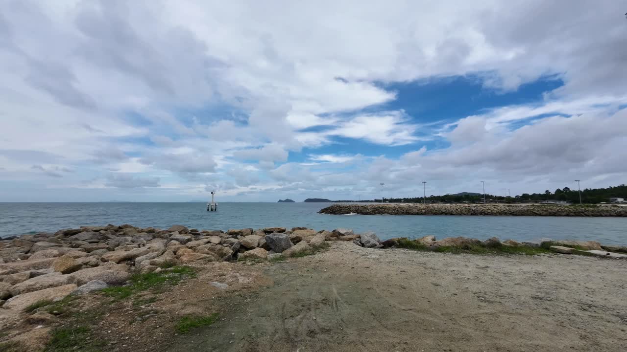 Timelapse footage of a lighthouse standing on the rocky coastline of Koh Phangan Thailand with dramatic clouds drifting across the tropical sky
