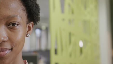 medio retrato de una feliz mujer de negocios afroamericana en la oficina, sonriendo, en cámara lenta, espacio de copia