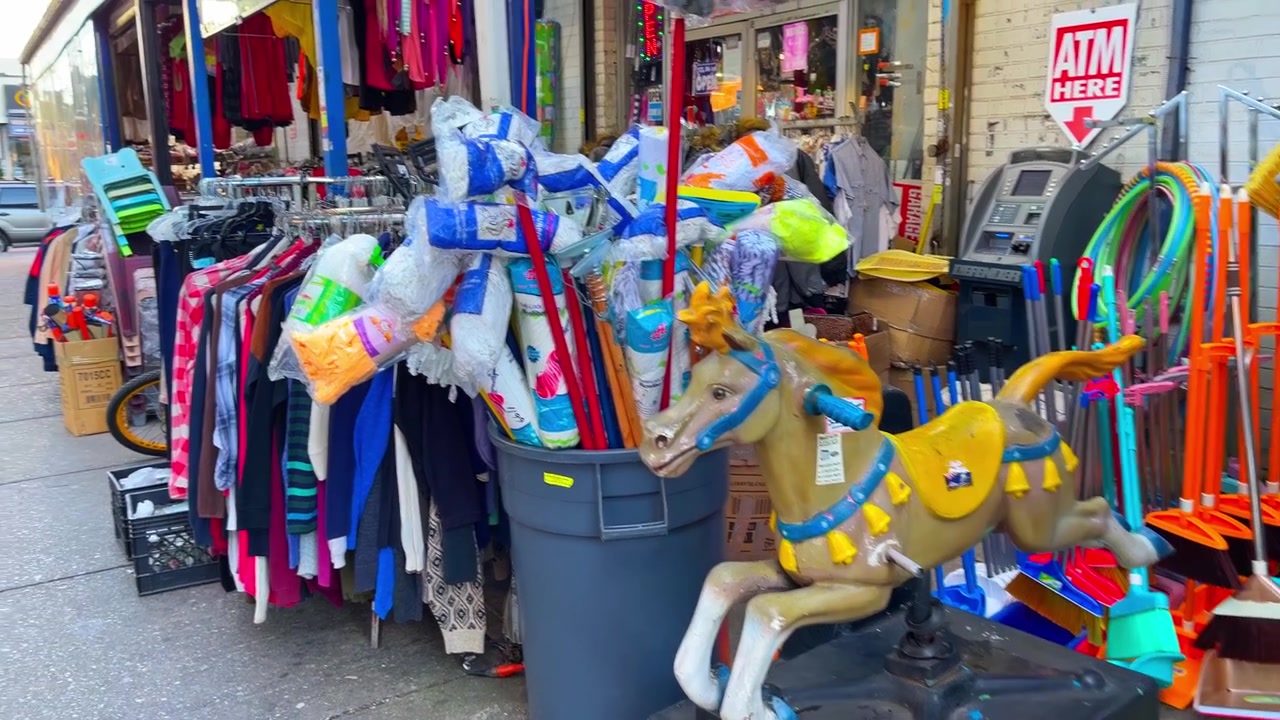 Nova Iorque, EUA, 9 de março de 2022: Exposição de mercadorias na calçada em frente a lojas de varejo no Queens. Araras de roupas e produtos de limpeza embalados exibidos em frente a lojas na calçada do Queens.