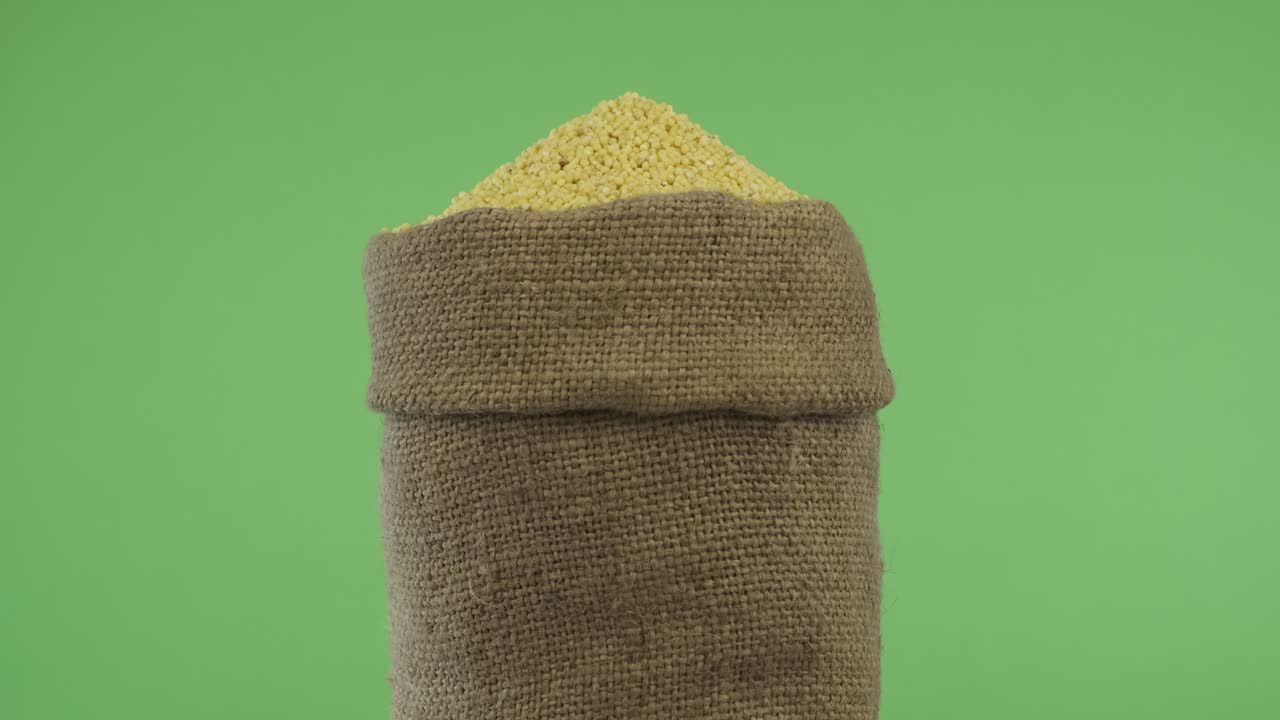 Rotating a full bag of millet grain. Close-up.