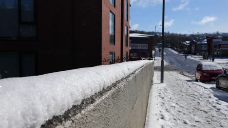 a snow topped wall in an urban city street on a sunny winter day