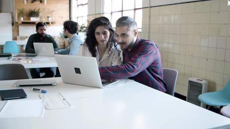 Smiling-handsome-young-man-setting-laptop-for-colleague