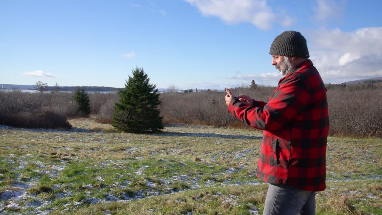 A man using his cell phone on a walk in the countryside. Stock video.