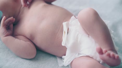 infant-with-pacifier-in-mouth-and-in-diaper-cries-on-table