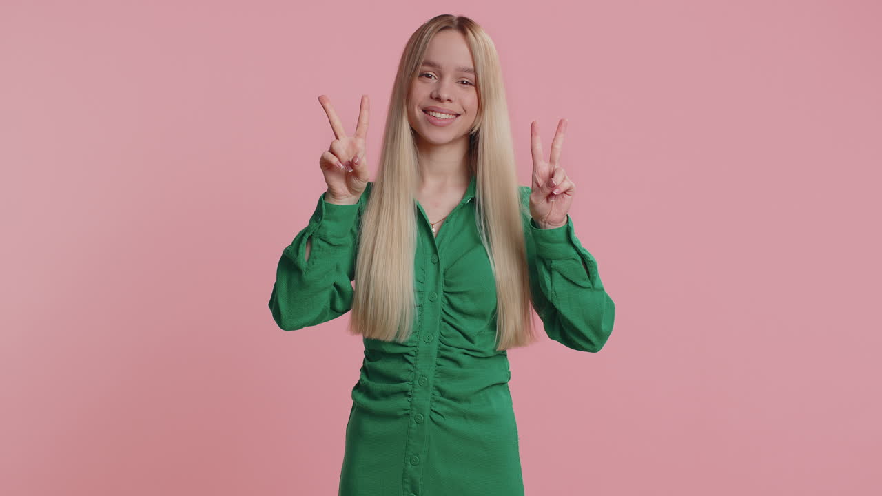 Young caucasian woman showing victory sign hoping for success and win doing peace gesture smiling