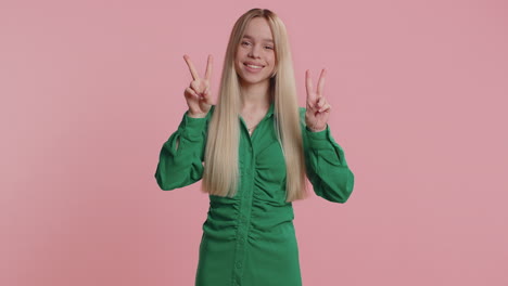 young caucasian woman showing victory sign hoping for success and win doing peace gesture smiling
