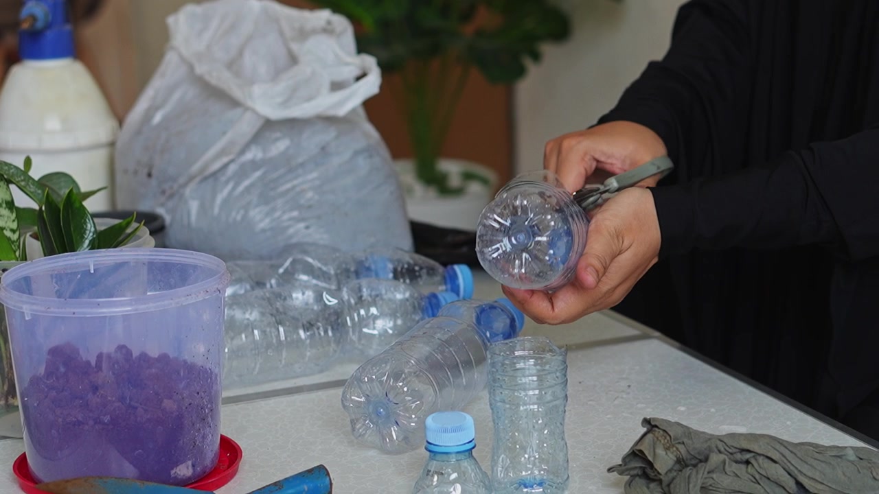 Video ASMR di giardinaggio sul taglio di bottiglie di plastica con le forbici per creare fioriere fai-da-te ecologiche.