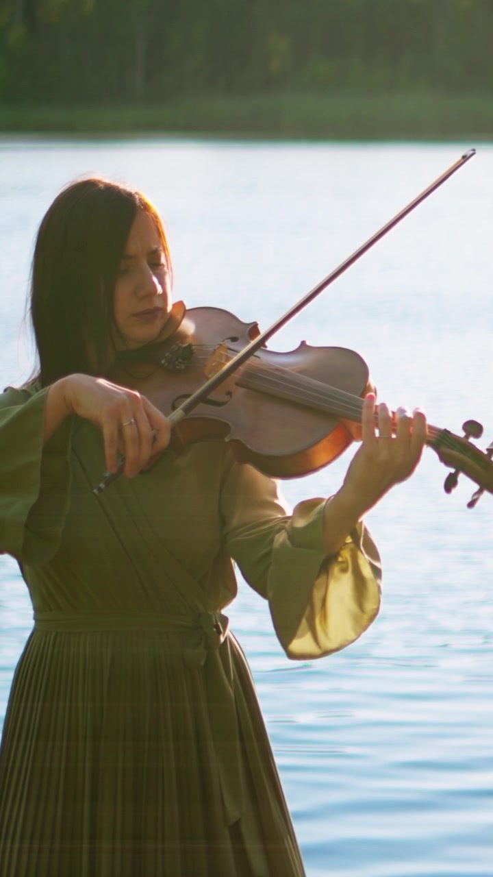 Woman Playing Violin by a Calm Lake at Sunset