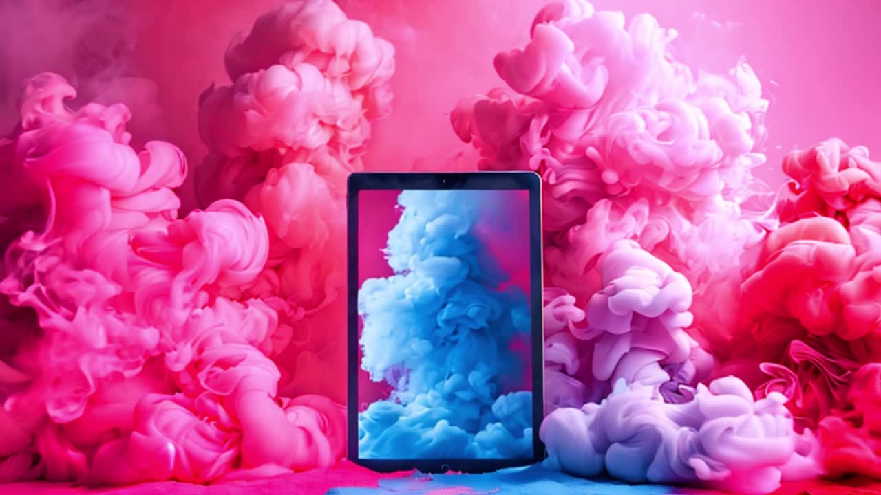 Digital tablet surrounded by vibrant pink and blue smoke clouds