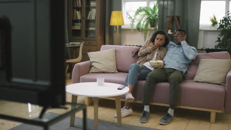 afro couple watching horror film at home