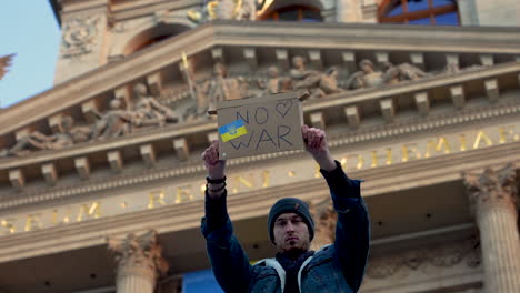 protester with sign against war in ukraine in front of museum, prague