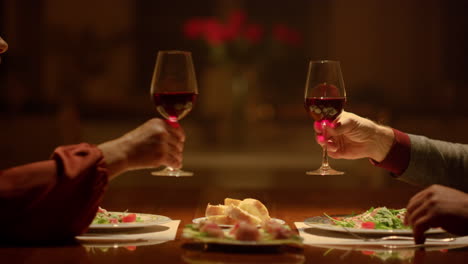 closeup clinking wine glasses in senior couple hands. grandparents toasting wine