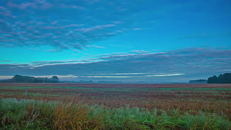 Clouds-Crawling-On-Blue-Sky-Over-Rural-Fields-In-A-Misty-Morning