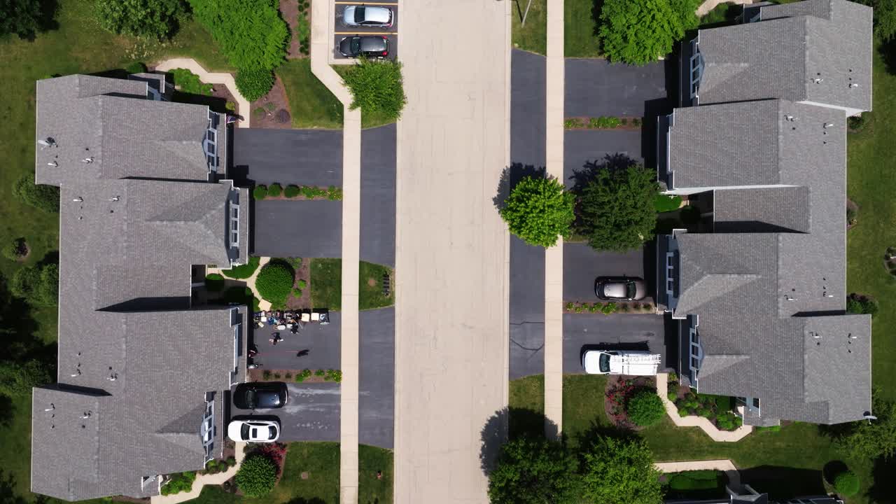 American suburb showing grid pattern streets and rooftops, asphalt driveways meeting tan roads, drone top shot