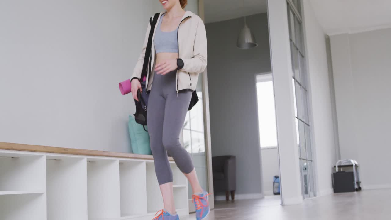 백인 여성 발레 댄서 가 스튜디오 에 들어와 미소 짓고 벤치 에 앉아 있다