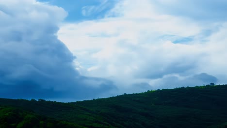 a picturesque view of a rolling green hill with fluffy white clouds in the blue sky.