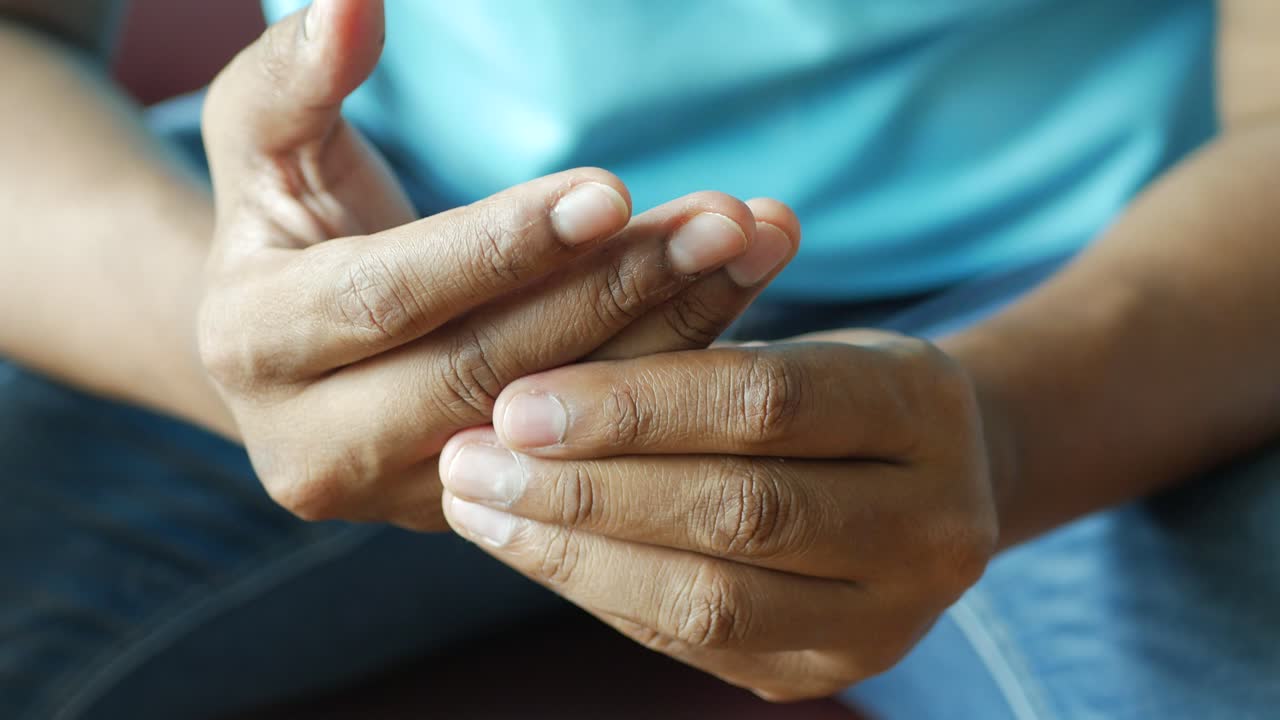 Gros plan des mains d'une personne montrant des signes de douleur ou d'inconfort.