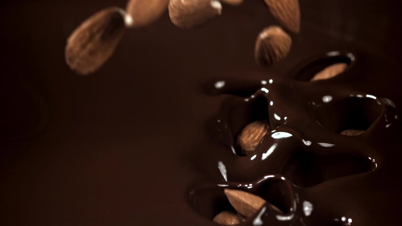 Amêndoas Caindo e Espirrando em Chocolate Amargo Derretido em Câmera Lenta