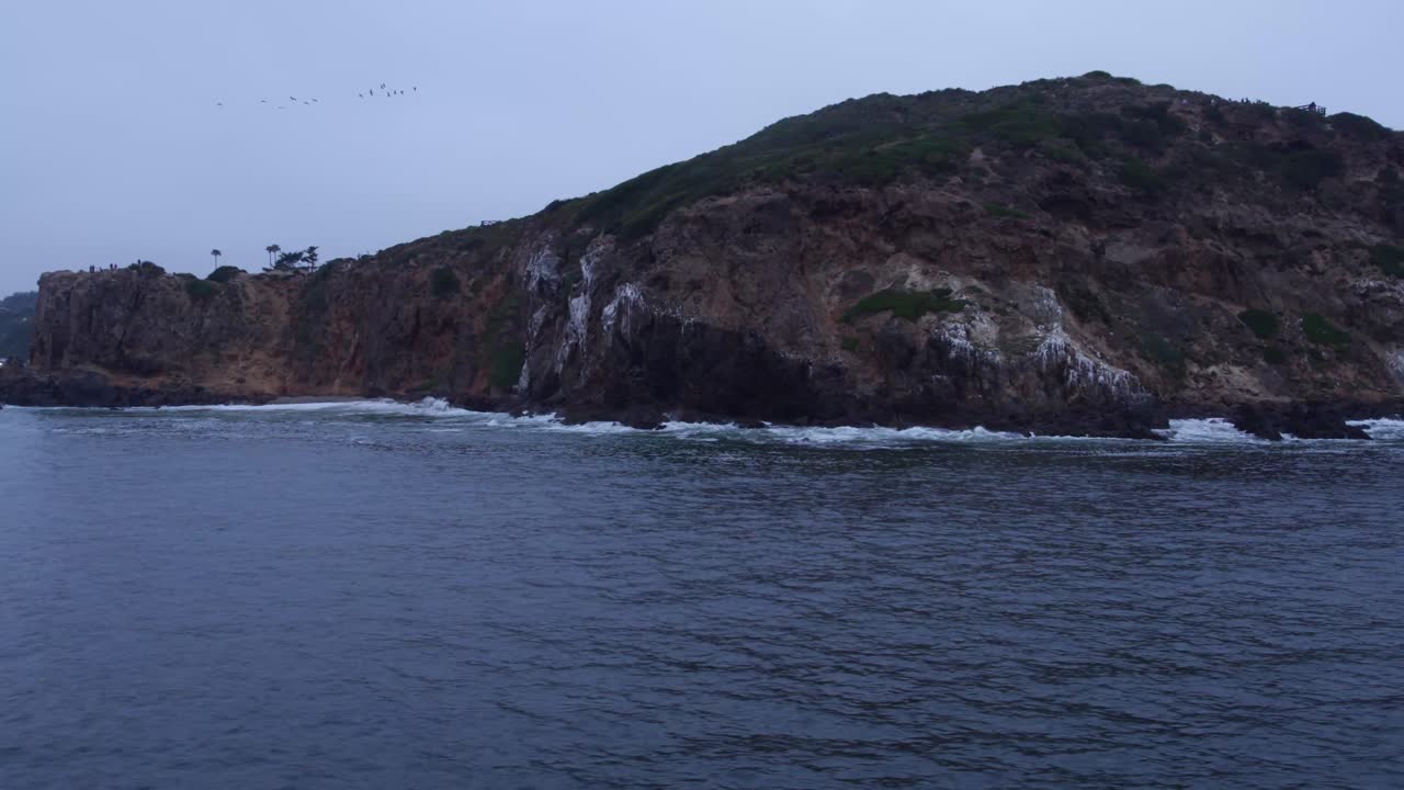 увлекательный вид на скалистые скалы вдоль побережья малибу в сумерках, с волнами, мягко бьющимися о скалистый берег
