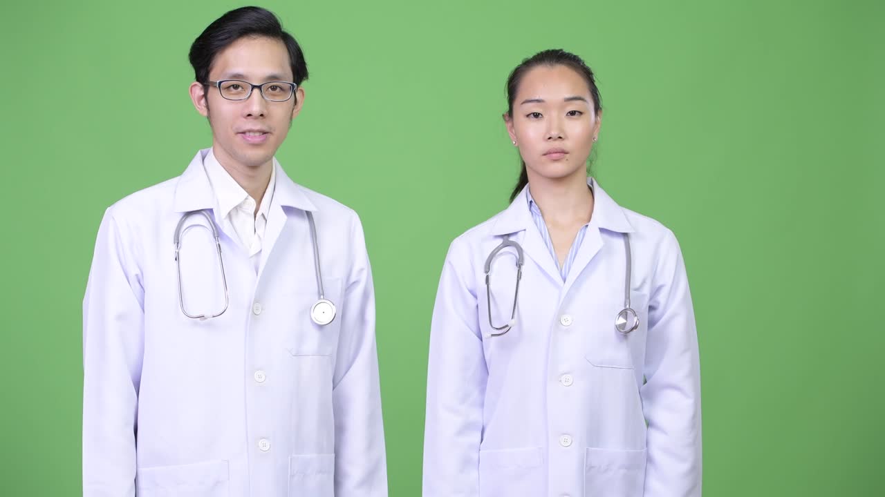 Young happy Asian couple doctors with arms crossed together