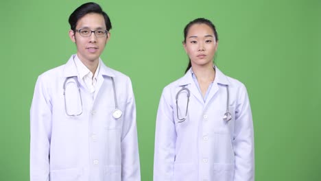 Young happy Asian couple doctors with arms crossed together