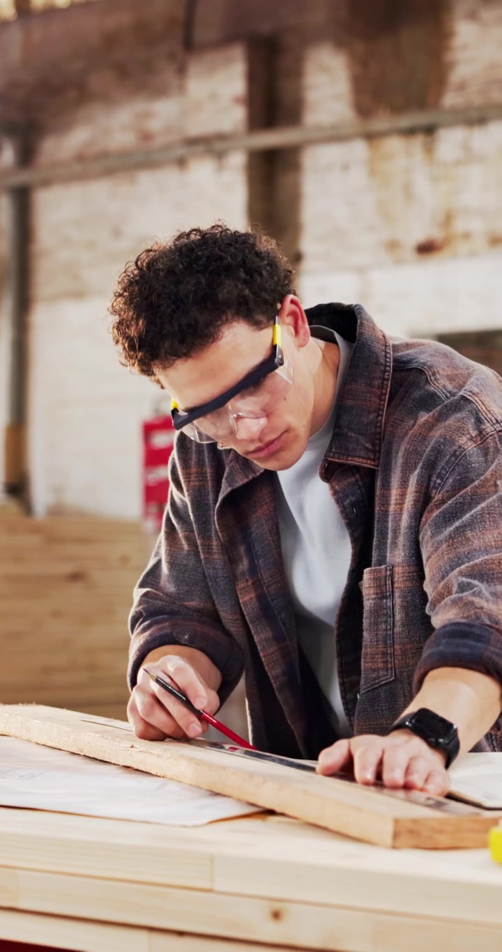 Young Carpenter Measuring and Marking Wood in Workshop