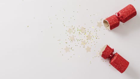 video of red christmas cracker, stars and decoration with copy space on white background