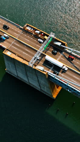 footage above the bridge over the deep river. suspension bridge with roads for transport traffic. top view on sunny day. vertical video