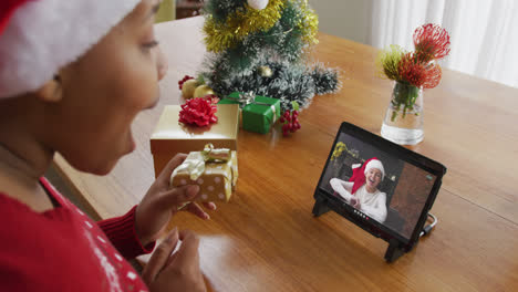 Mujer-Afroamericana-Con-Sombrero-De-Santa-Usando-Tableta-Para-Videollamada-Navideña-Con-Mujer-En-Pantalla