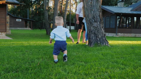 young couple playing with their little son in the backyard of the house