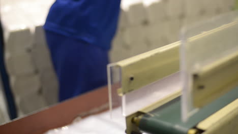 Factory-worker-filling-a-bag-with-plastic-bags-in-a-production-line